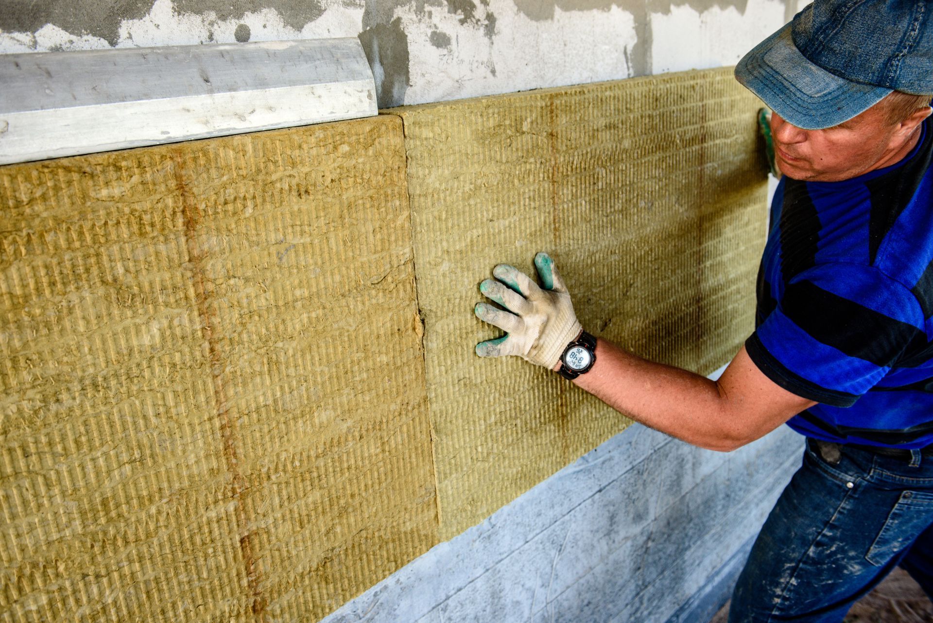 a man is installing rock wool insulation on a wall .