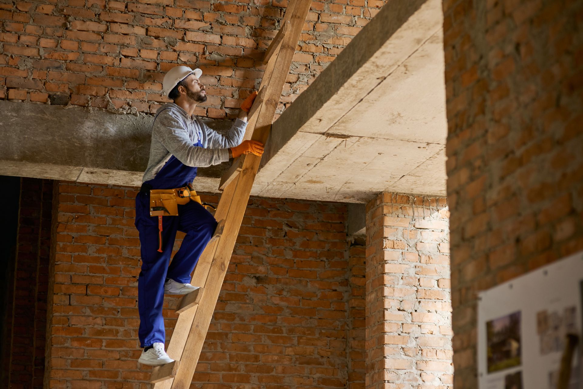 a man is standing on a wooden ladder in a building under construction .