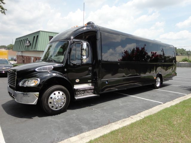 A black bus is parked in a parking lot next to a building.