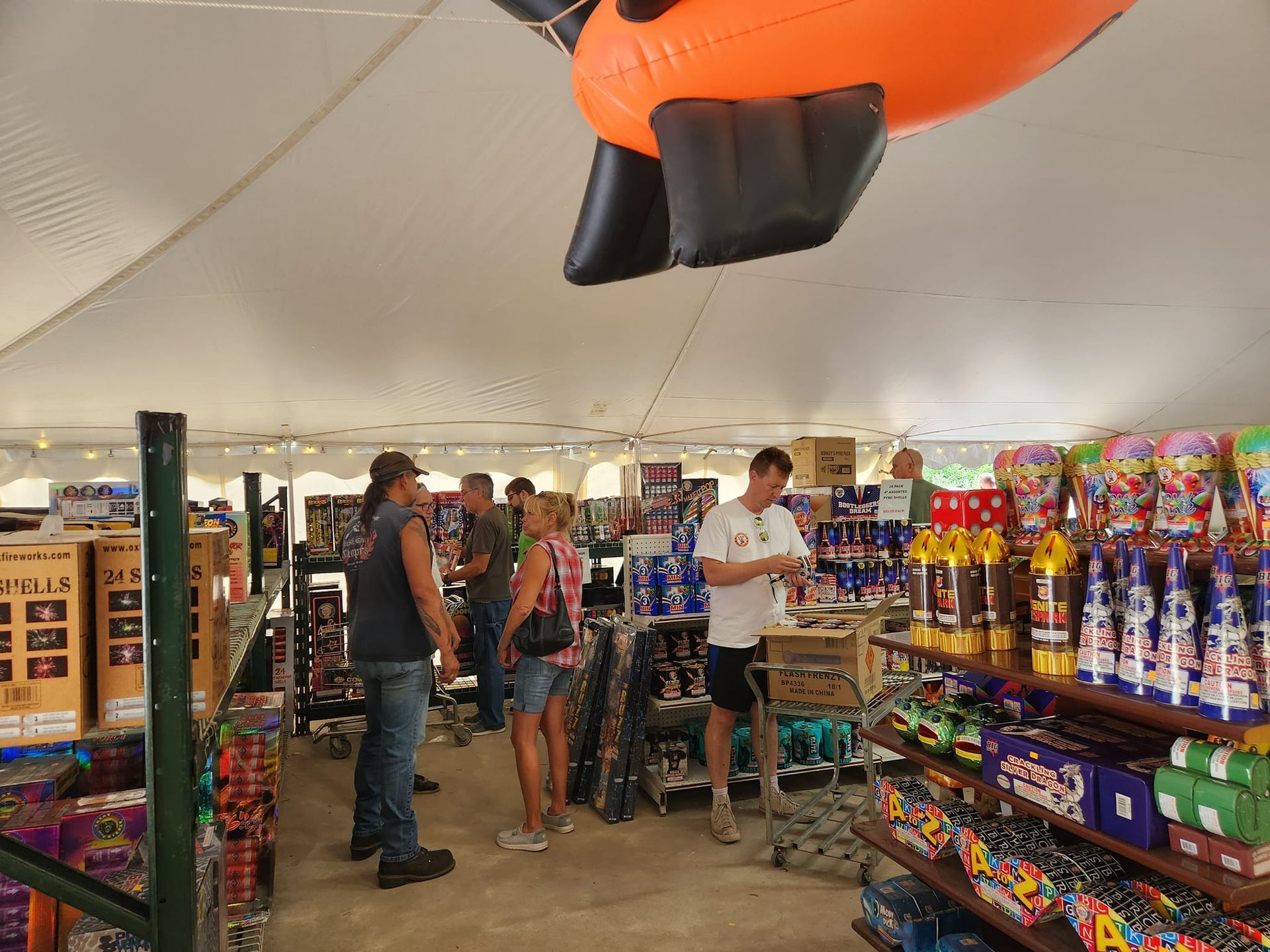 A group of people are standing in a store looking at fireworks.