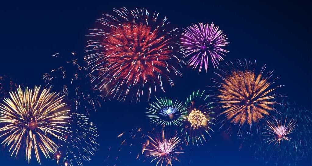 Fireworks are exploding over a city skyline at night.