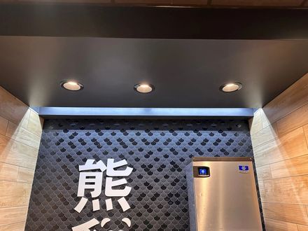 A dark ceiling with three recessed lights above a wall featuring a black patterned tile and white Chinese character.