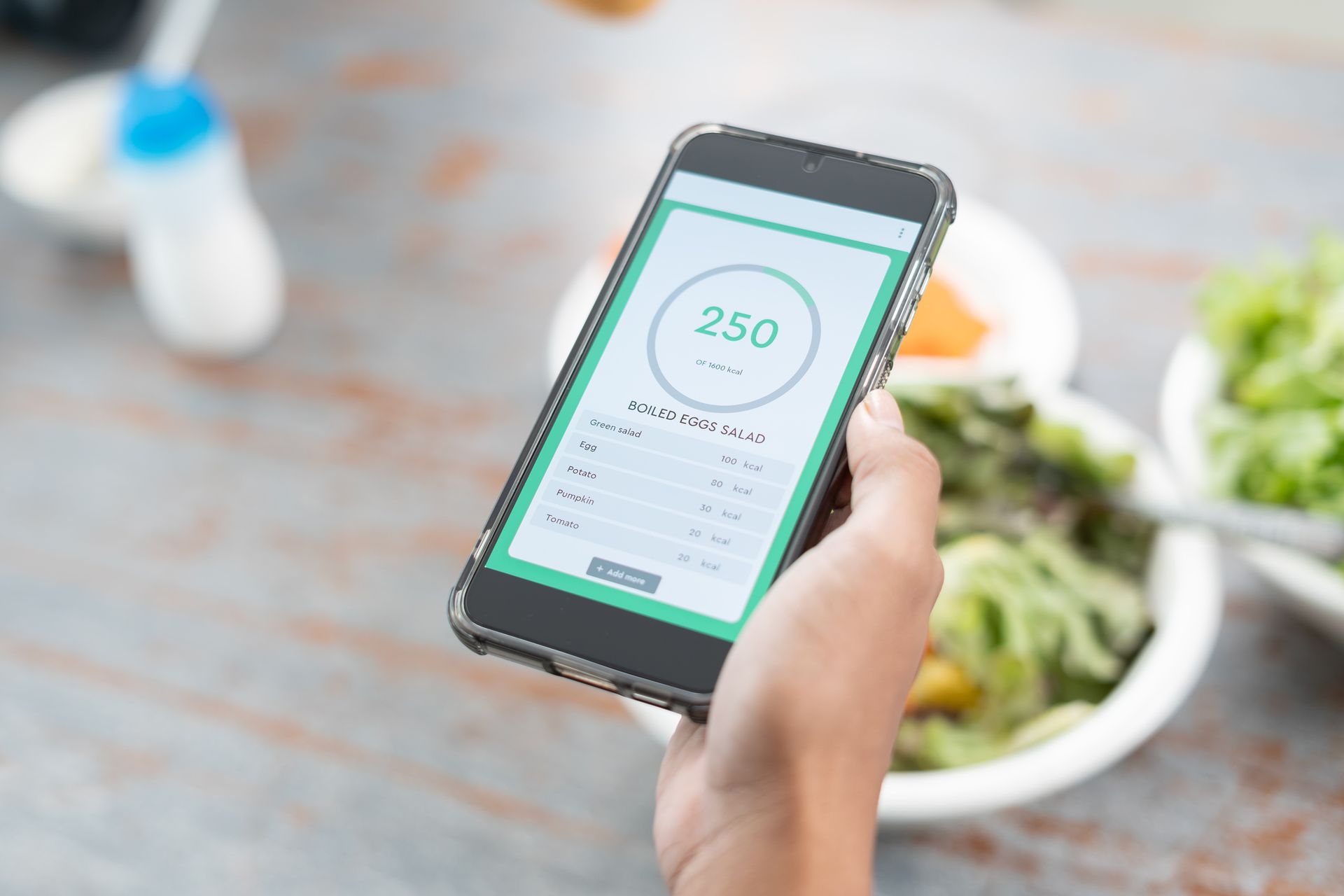 A young woman using a calorie counter app on a smartphone as part of a weight loss program