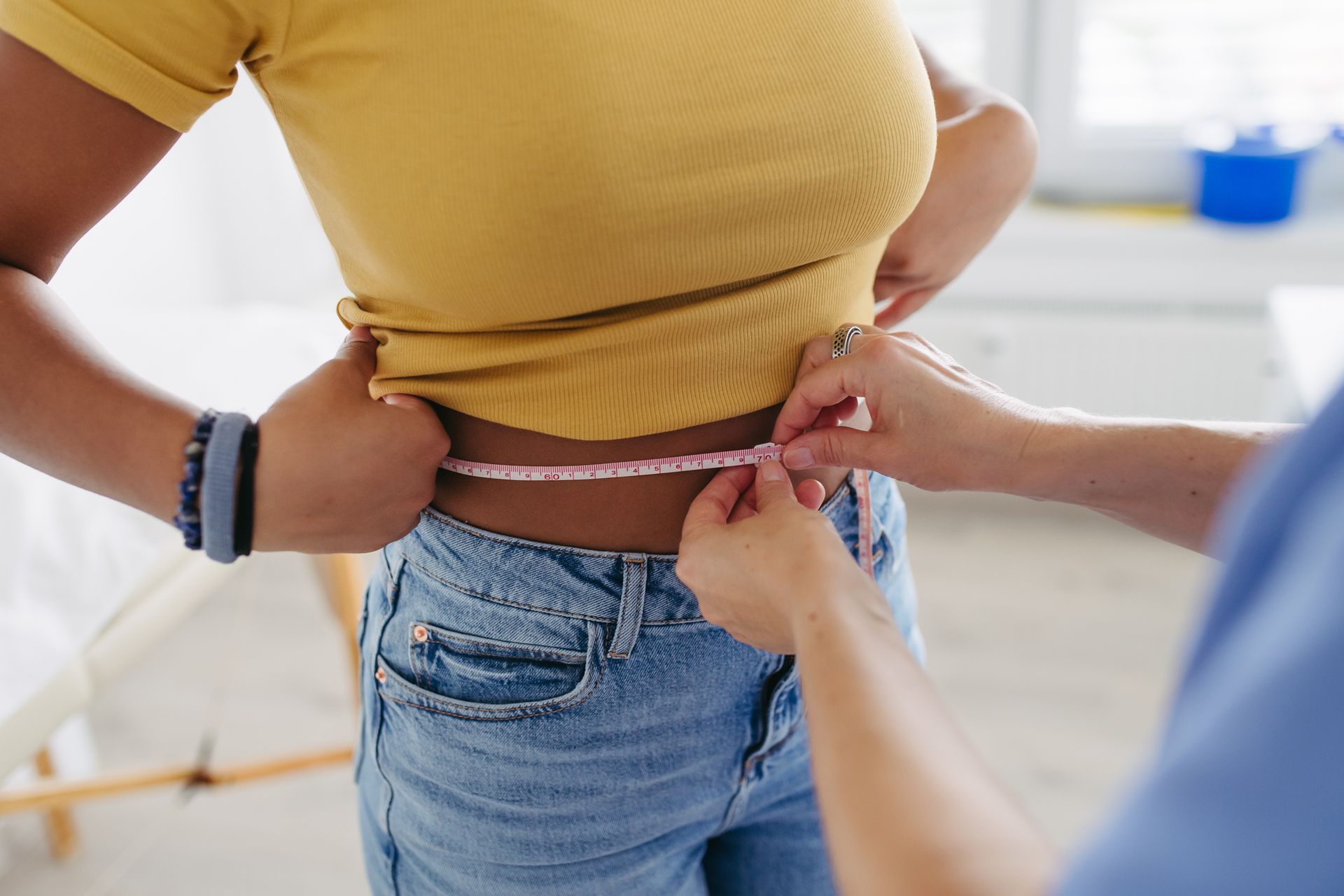 Waist measurement in clinical setting shows progress tracking for effective weight loss treatment.