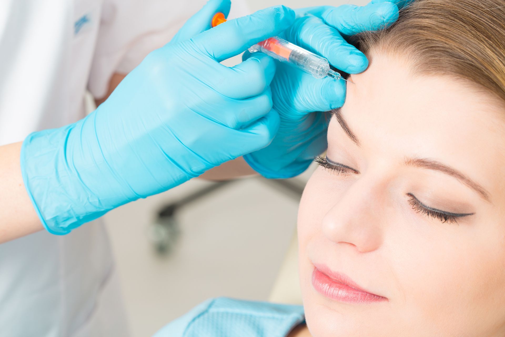 A woman is getting a botox injection in her forehead.