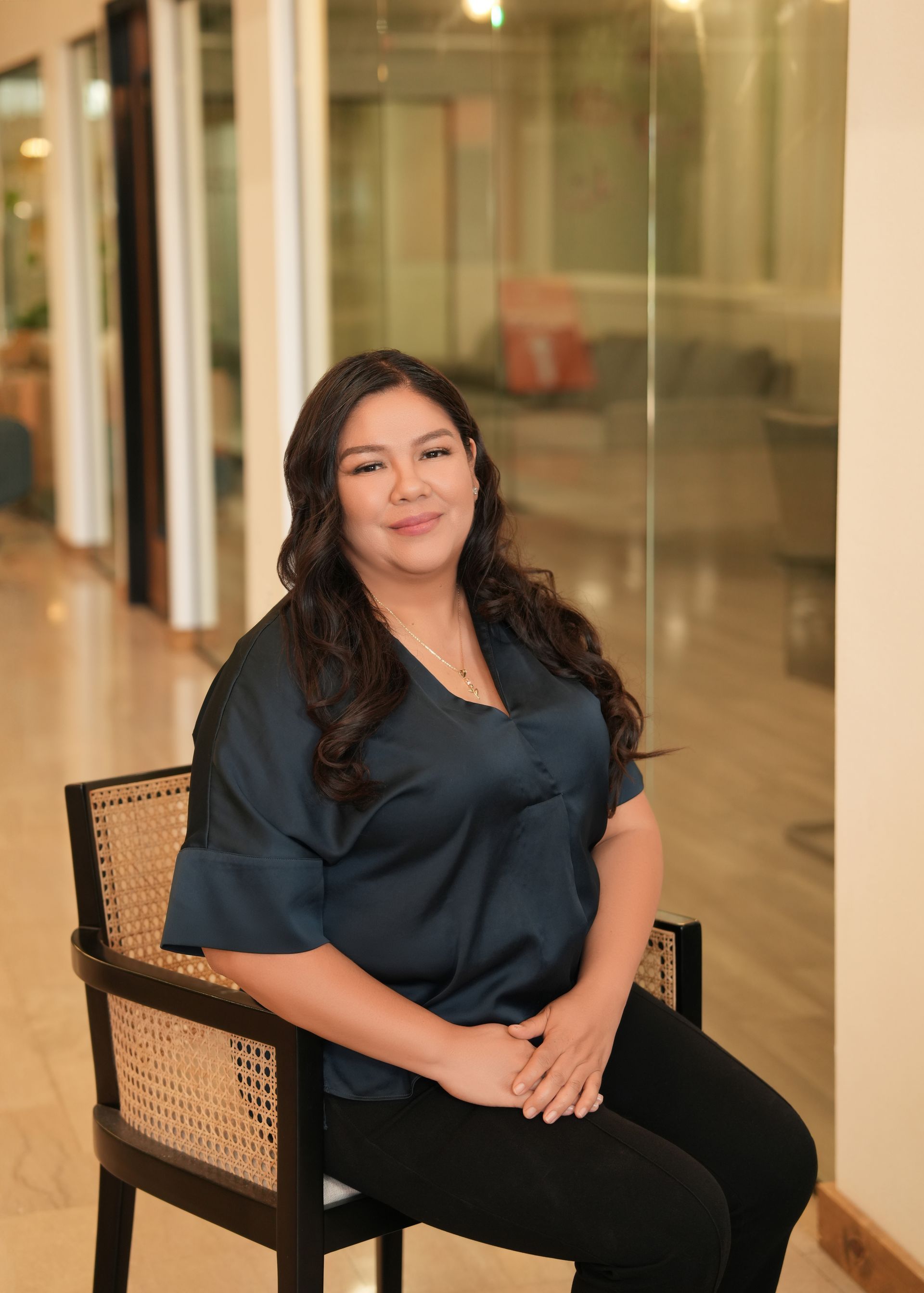 A woman is sitting in a chair in front of a glass wall.