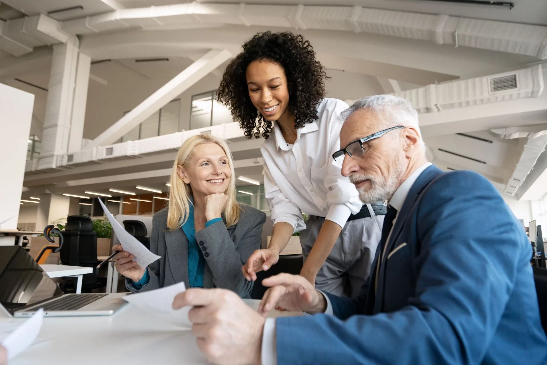 A doctor is sitting at a table talking to two elderly people.