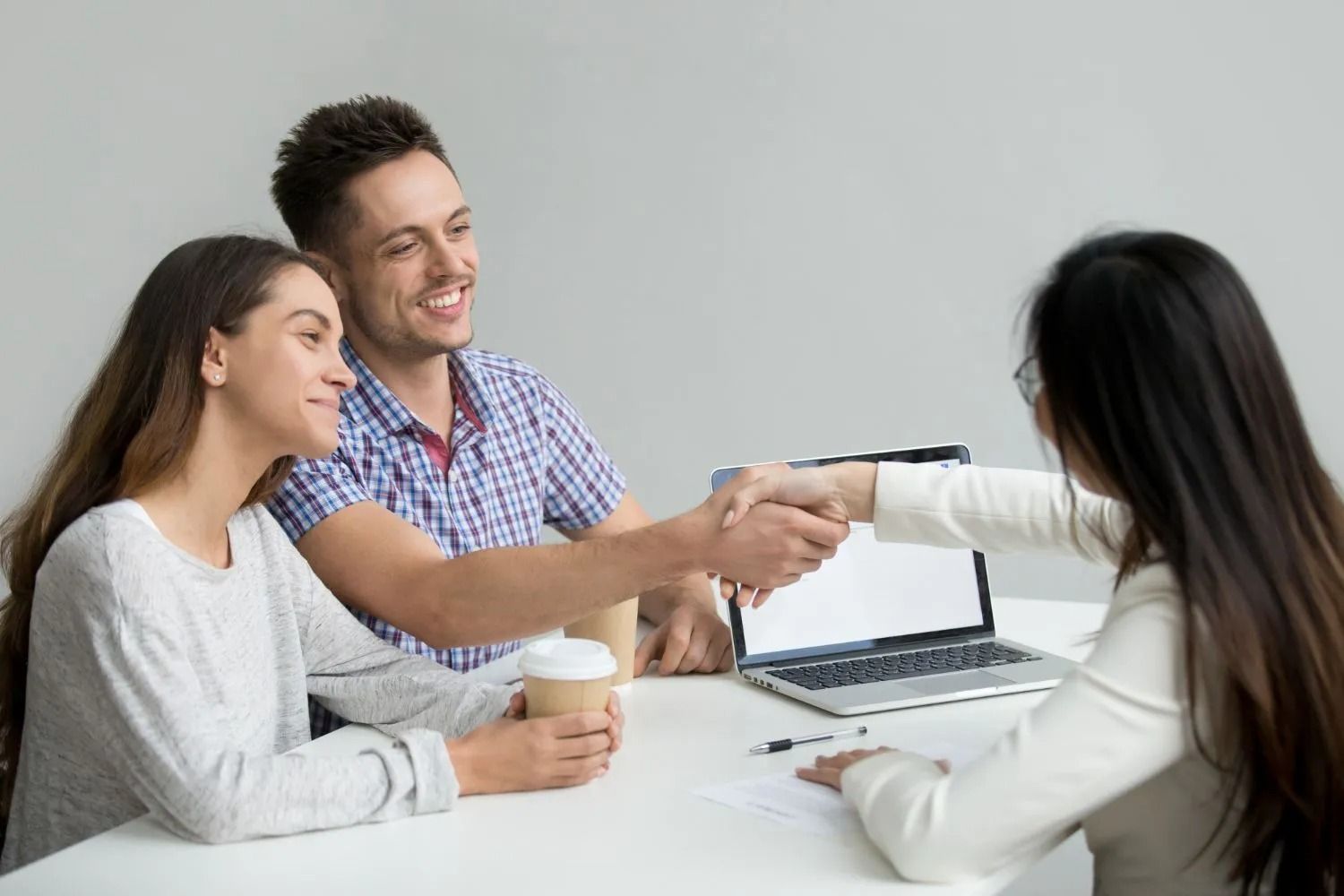 A doctor is sitting at a table talking to two elderly people.