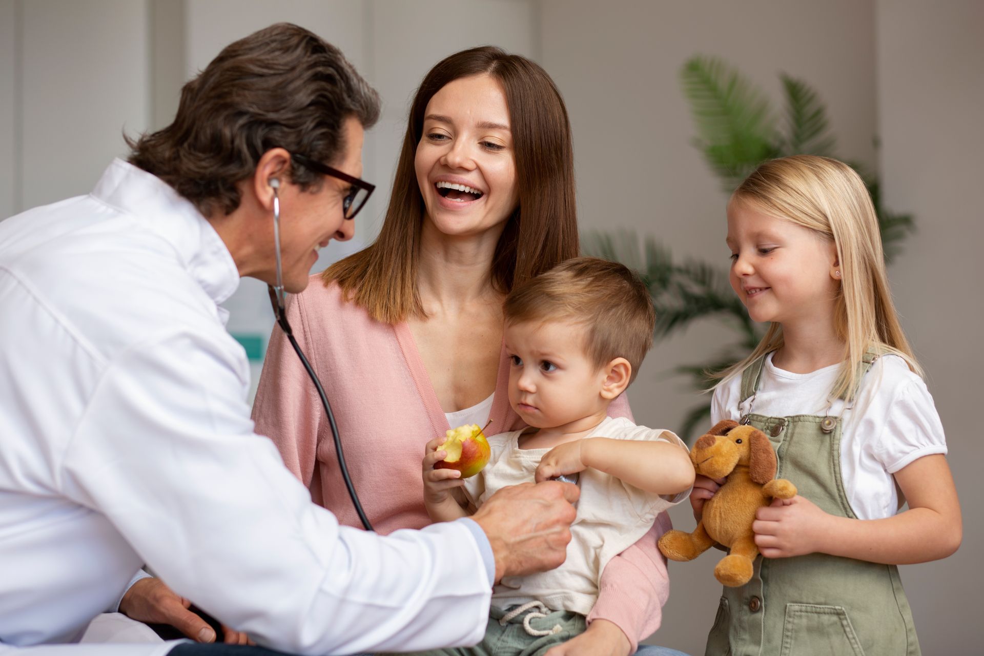 A doctor is sitting at a table talking to two elderly people.