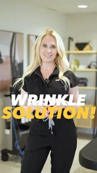 A woman in a black jumpsuit is standing in front of a sign that says wrinkle solution.