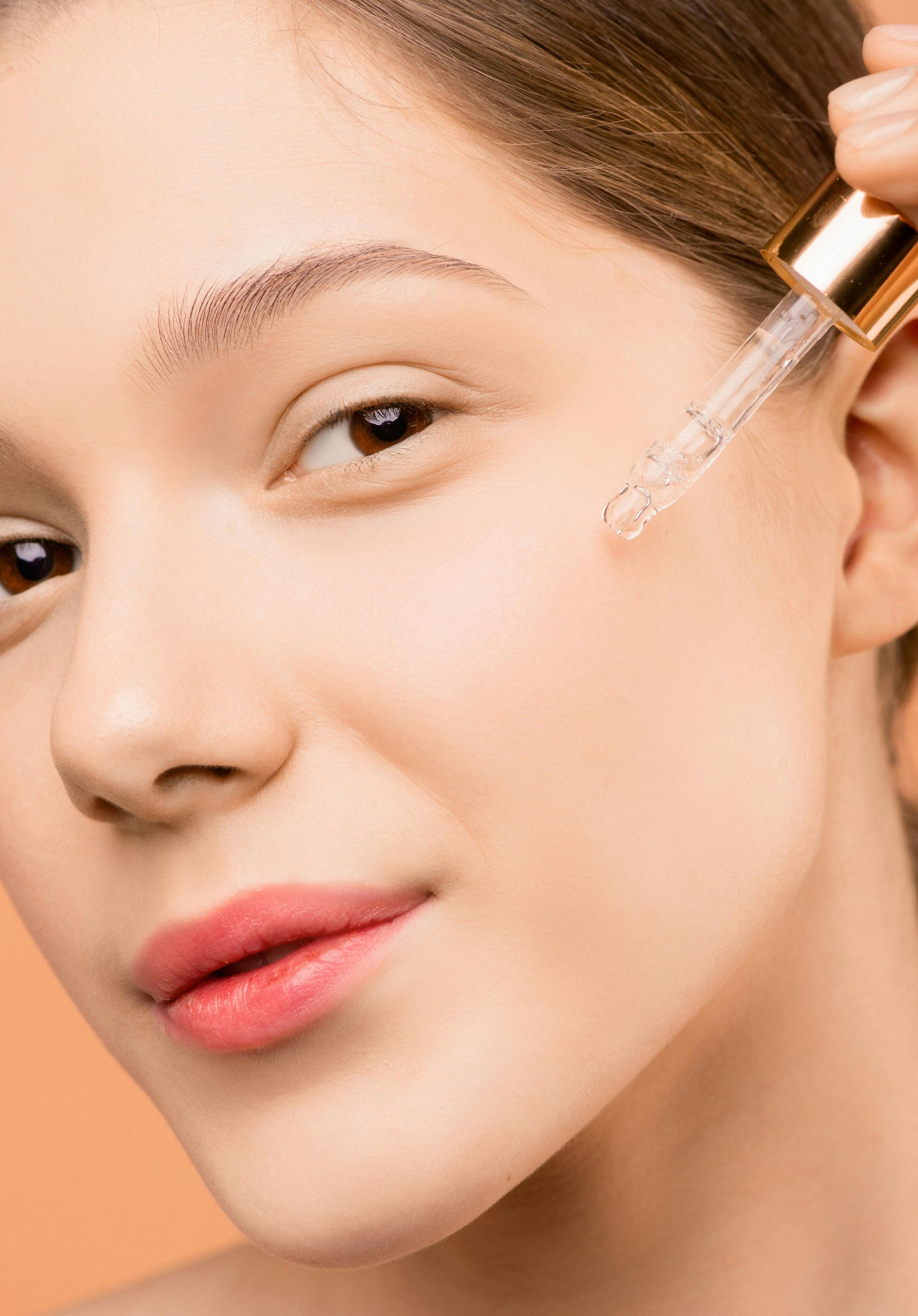 A woman is applying a serum to her face with a pipette.