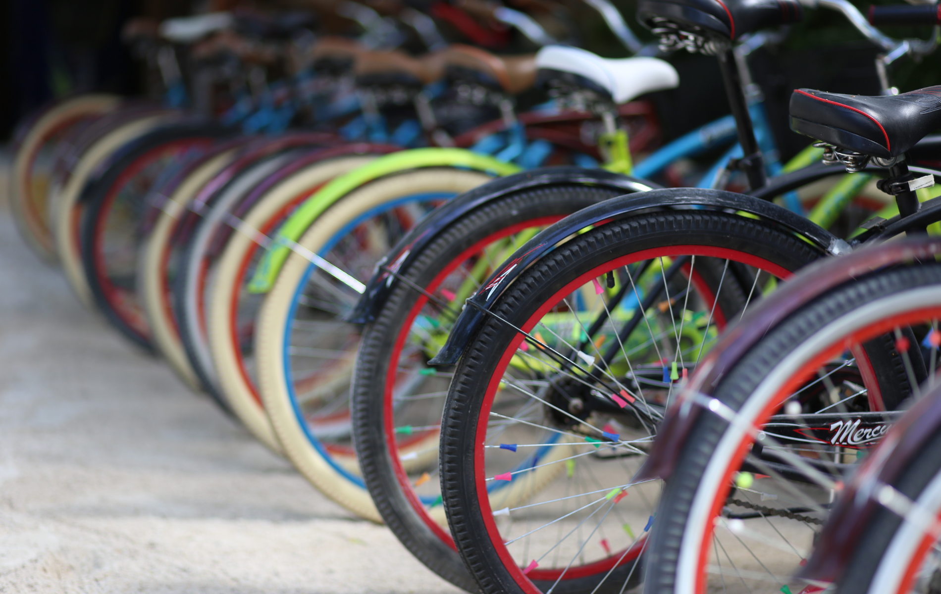 A row of bicycles are parked next to each other on a sidewalk.