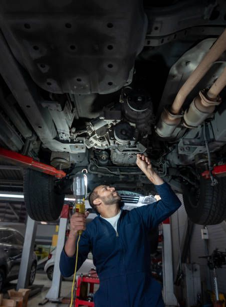 A Mechanic is Working Under a Car in a Garage — Smyrna, GA — All Pro Transmission