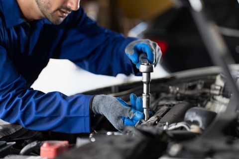 A Man Wearing Blue Gloves is Working on a Car — Smyrna, GA — All Pro Transmission Exchange LLC