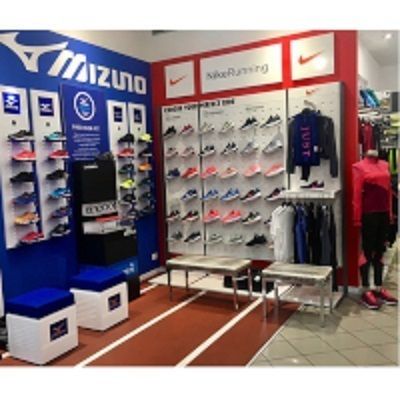 Interno di un negozio di scarpe da corsa con esposizione di prodotti Mizuno e Nike. Pista rossa sul pavimento.