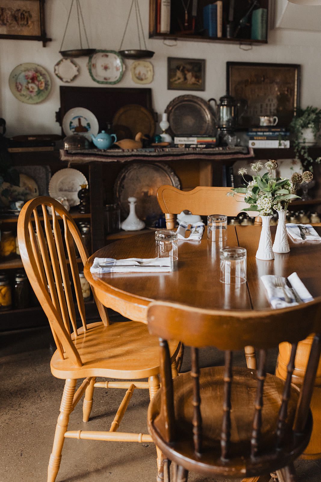 A wooden table and chairs in a room with plates on the wall.