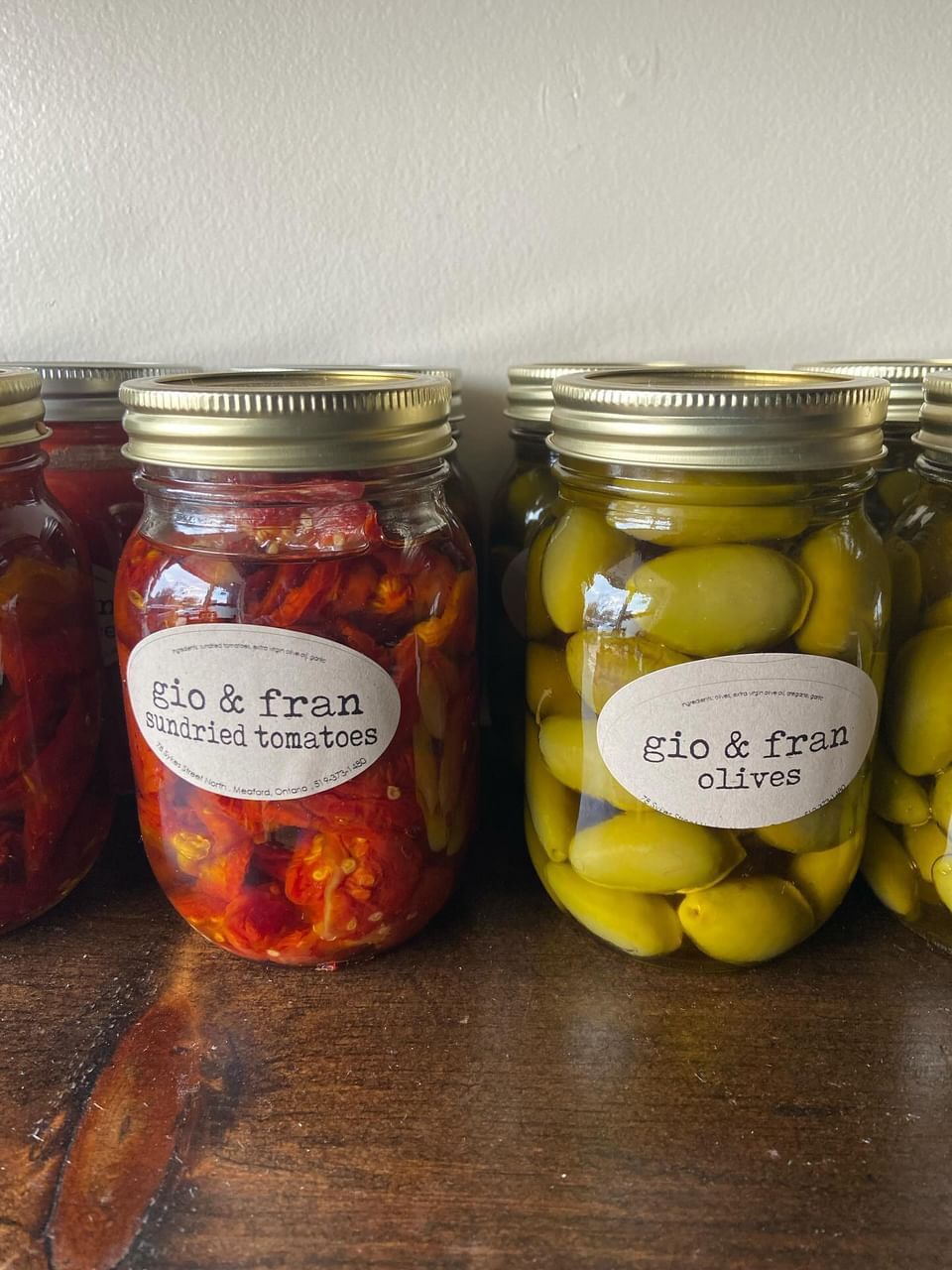 A row of jars filled with different types of food on a wooden table.