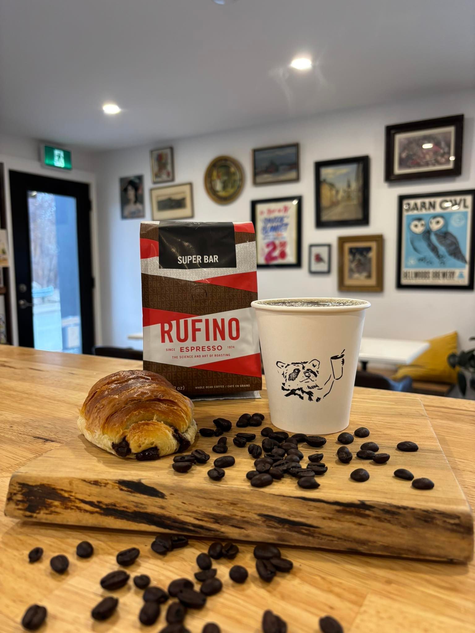 A cup of coffee and a bag of coffee beans are on a wooden table.