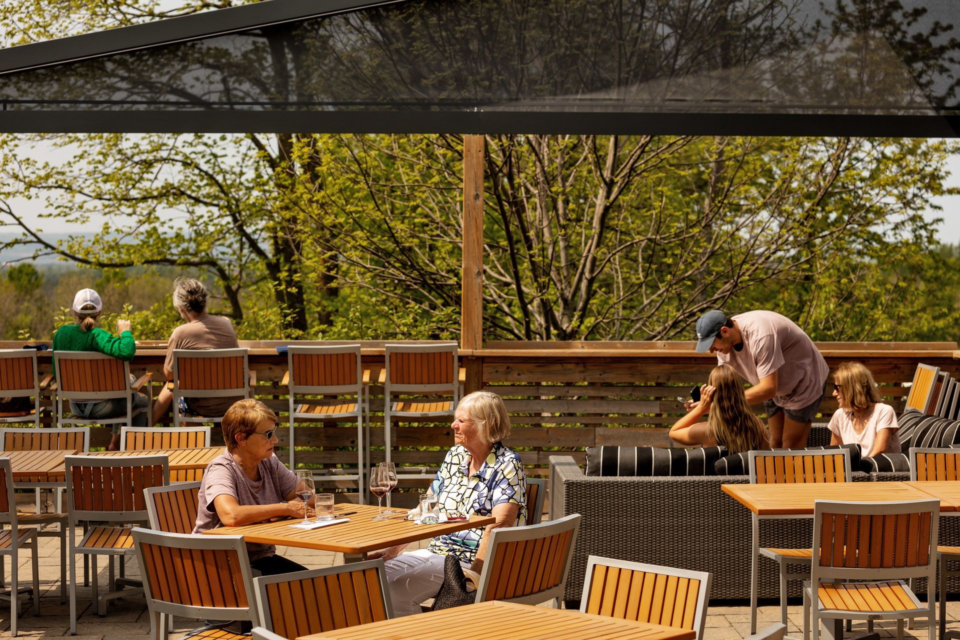 A group of people are sitting at tables on a patio.