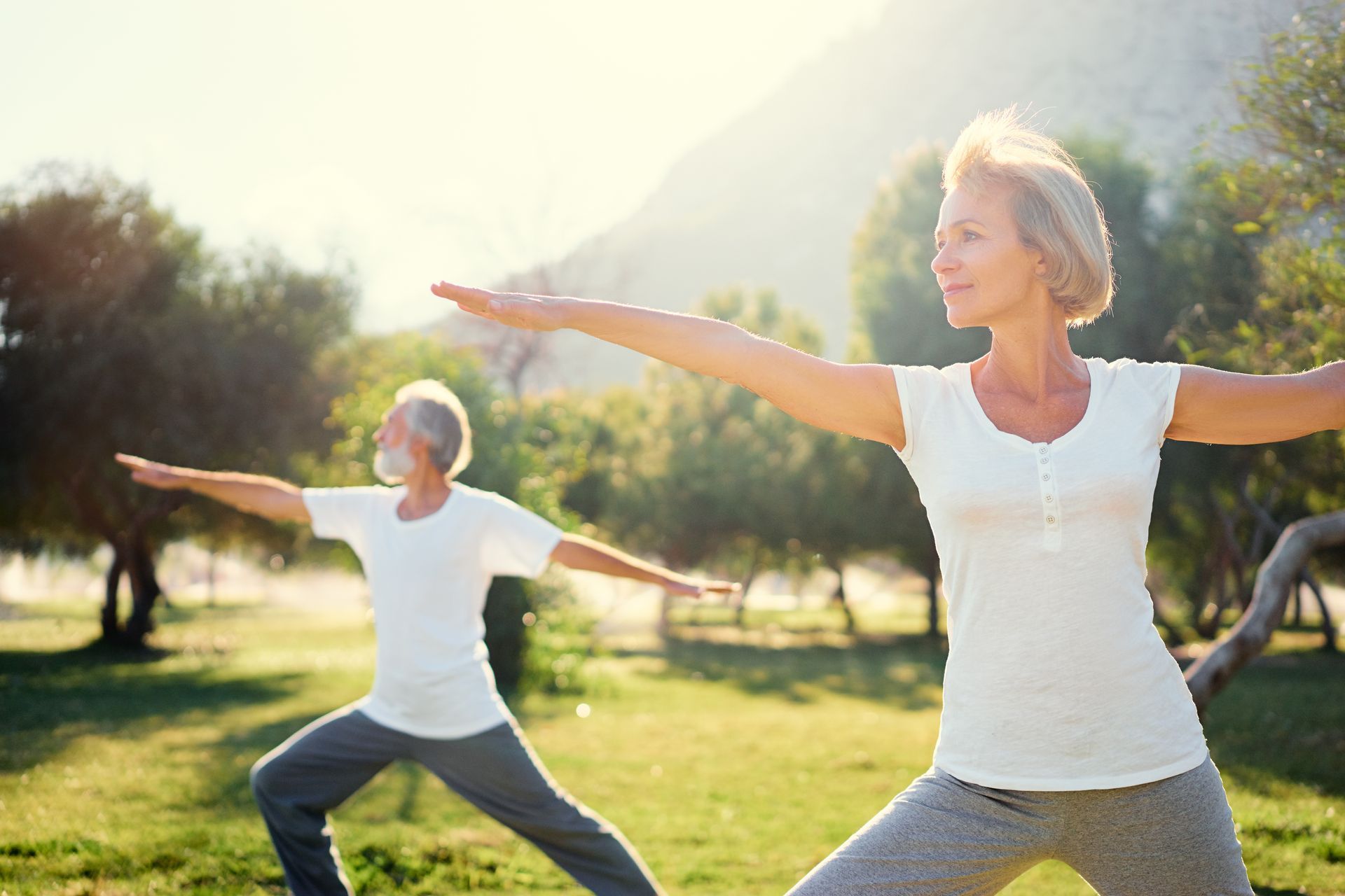A man and a woman are practicing yoga in a park.