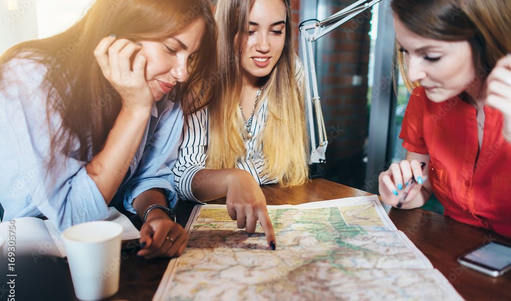 Three women are sitting at a table looking at a map.