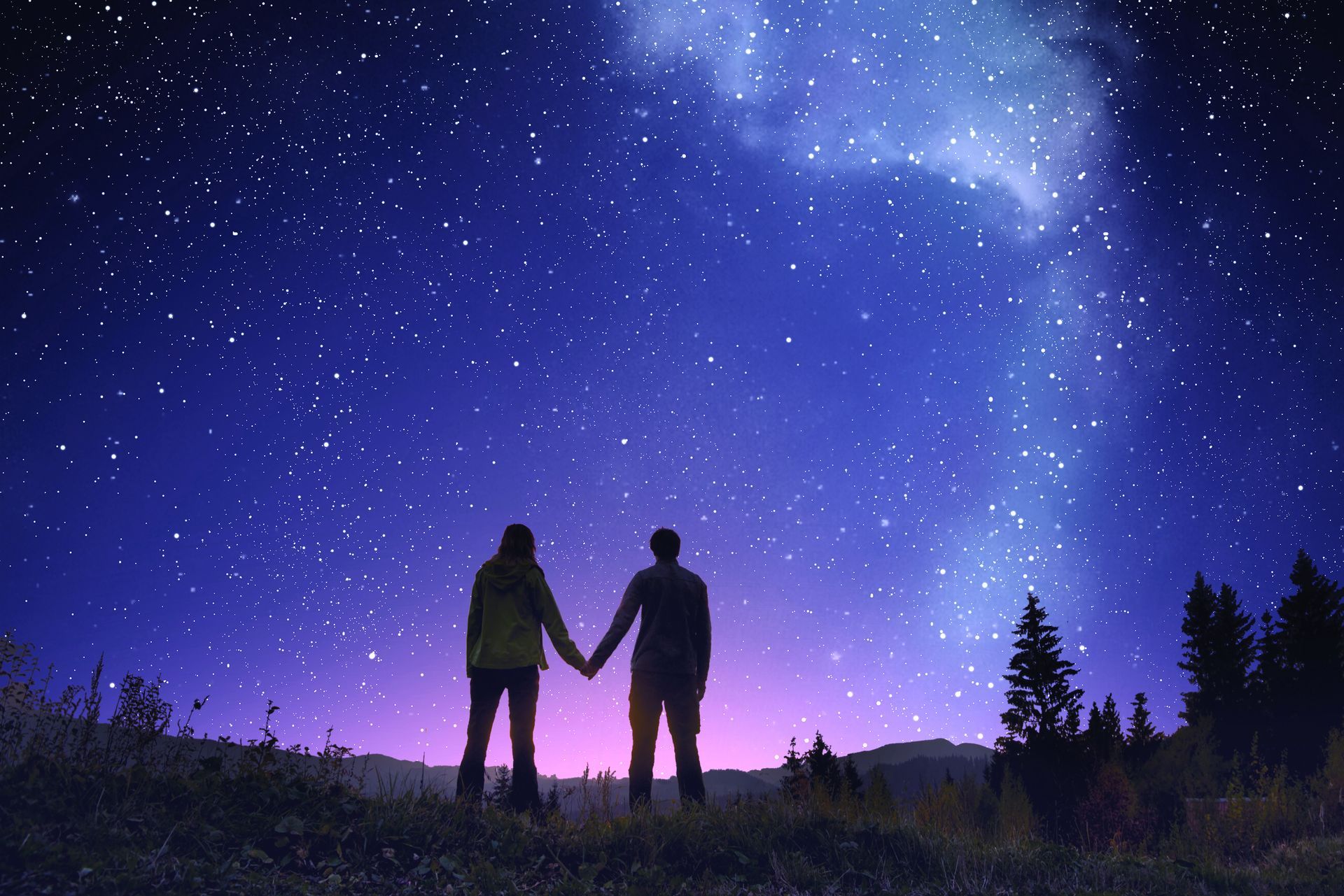 A man and a woman are holding hands under a starry night sky.