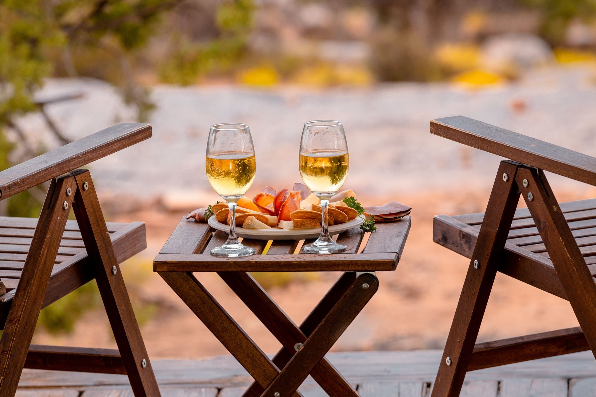 Two people are toasting with wine glasses in front of a fire pit.