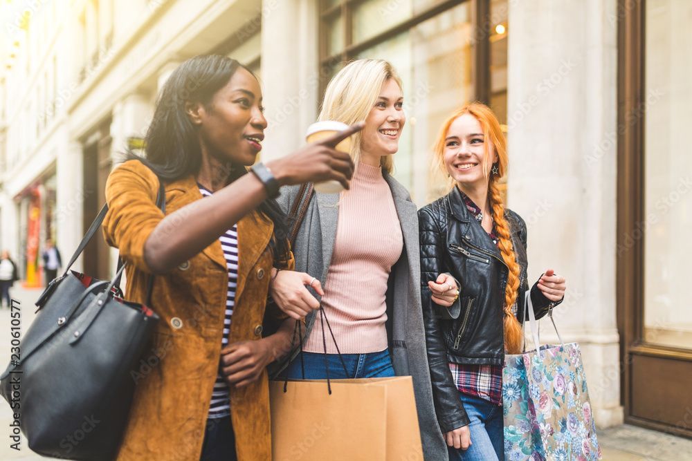 Three women are walking down the street with shopping bags.