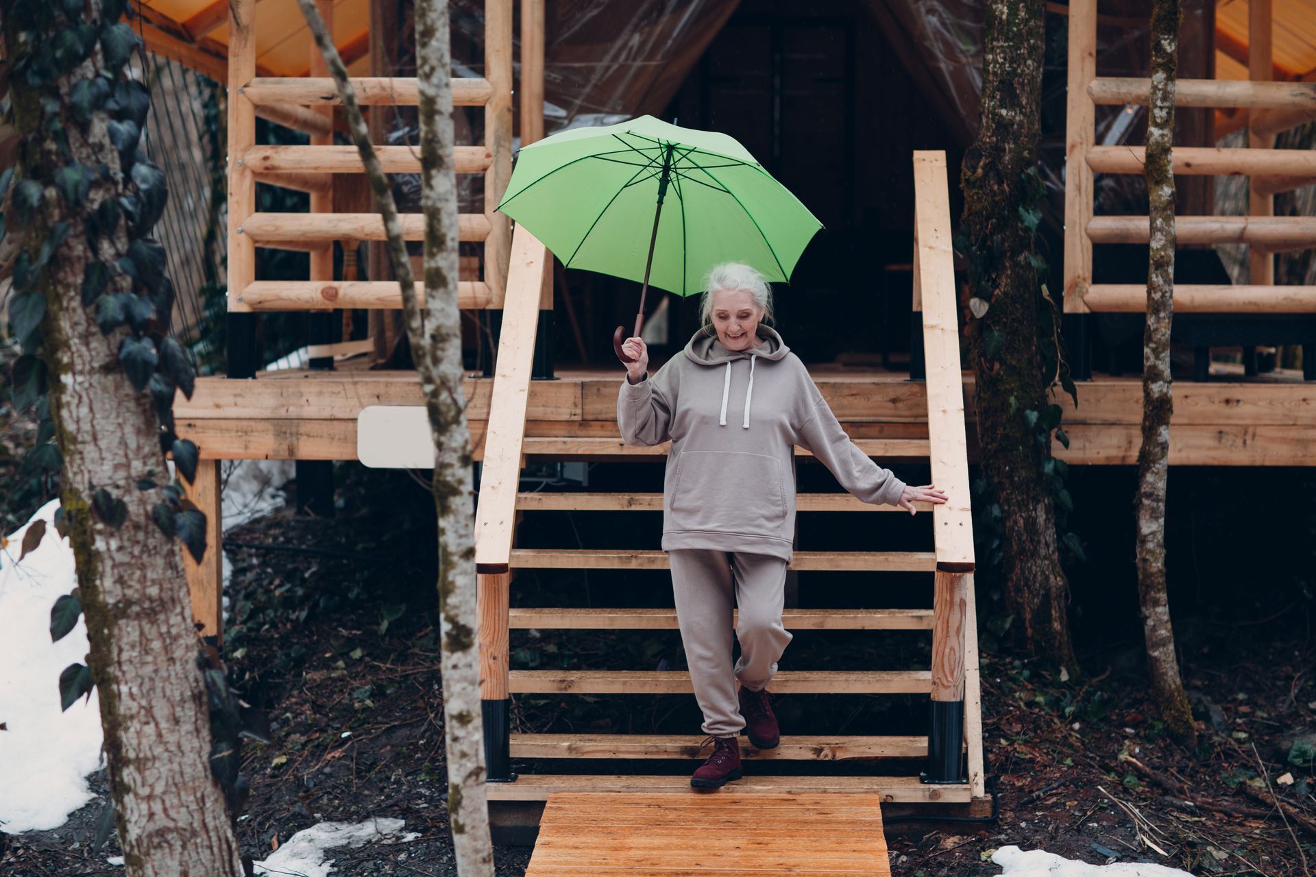 A woman is holding a green umbrella while walking down stairs.