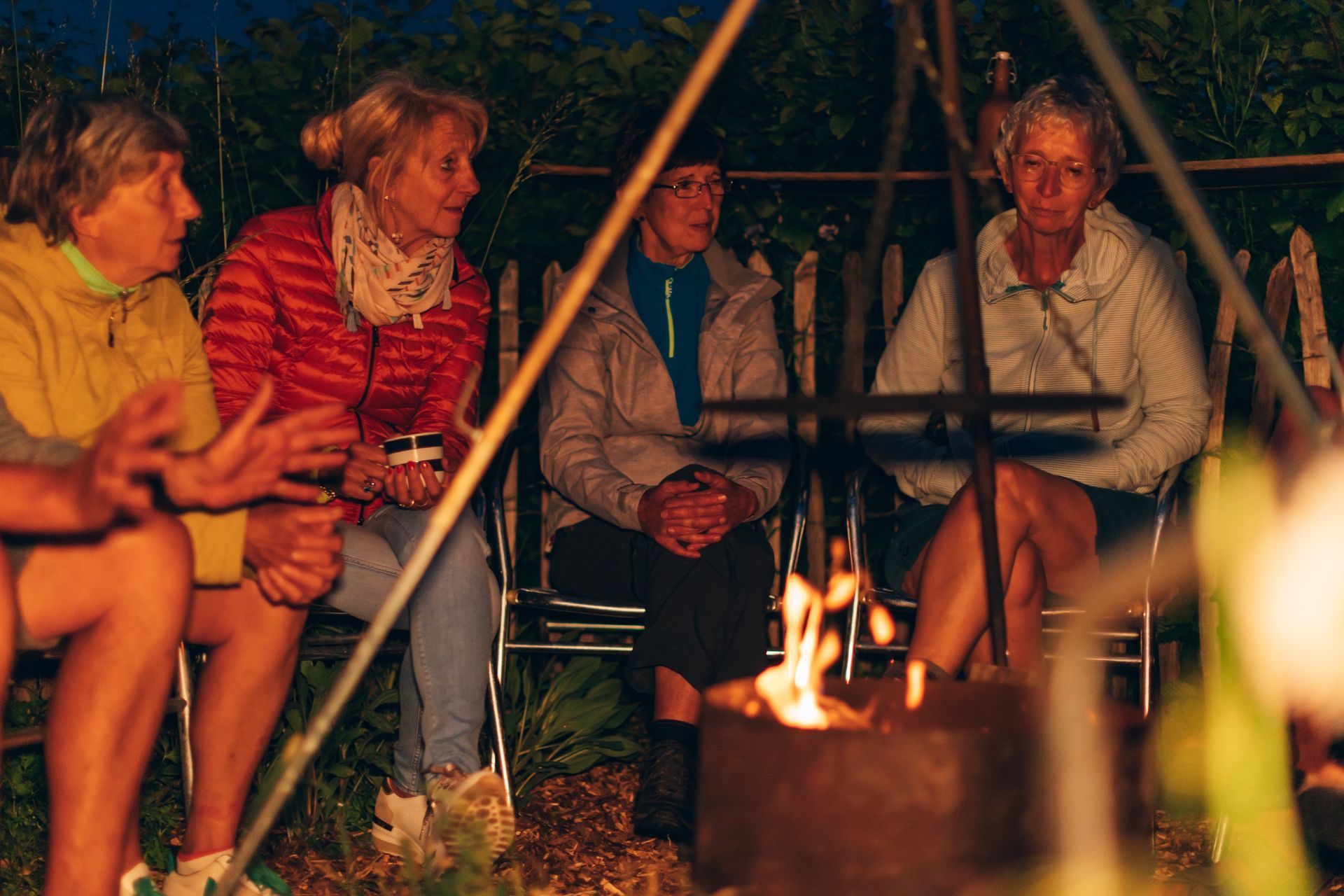 A group of people are sitting around a campfire at night.