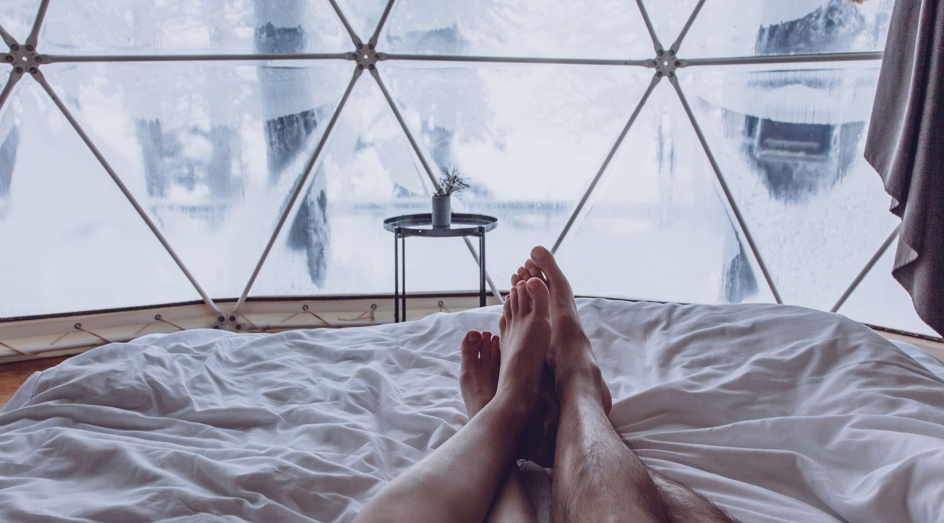 A couple 's feet are laying on a bed in a dome.