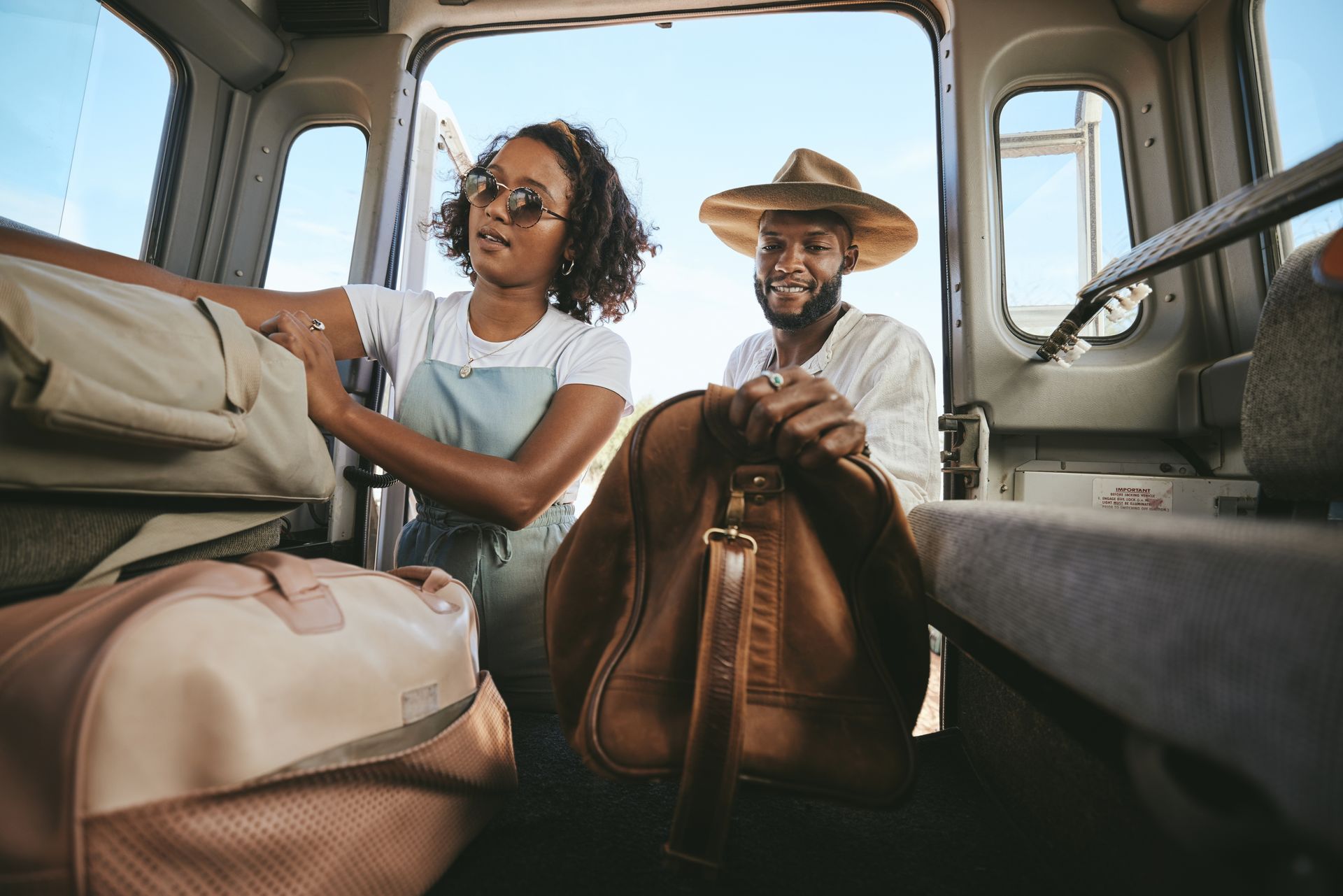 A man and a woman are sitting in the back of a car with luggage.