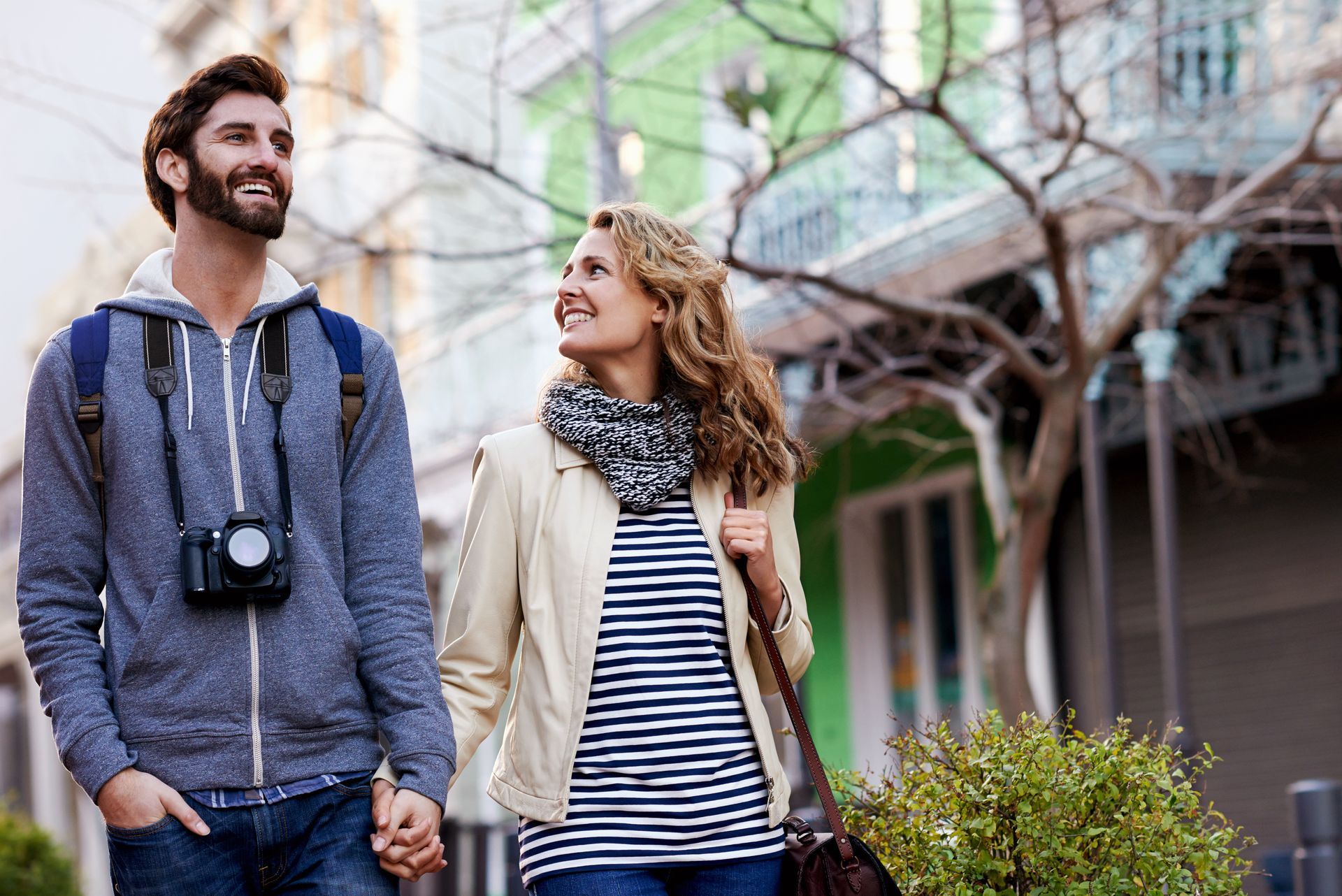 A man and a woman are walking down the street holding hands.