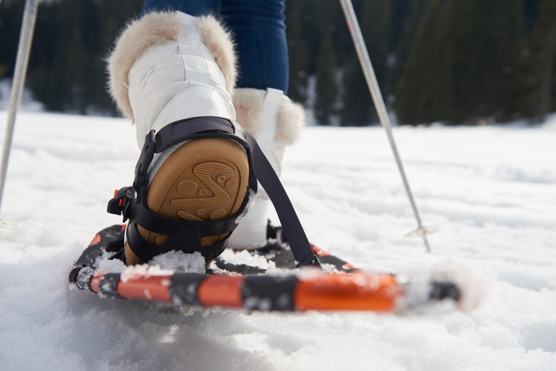 A person wearing snow shoes is walking through the snow.