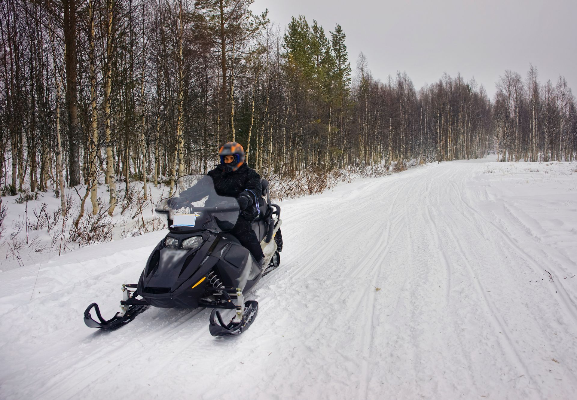 A man is riding a snowmobile down a snowy road