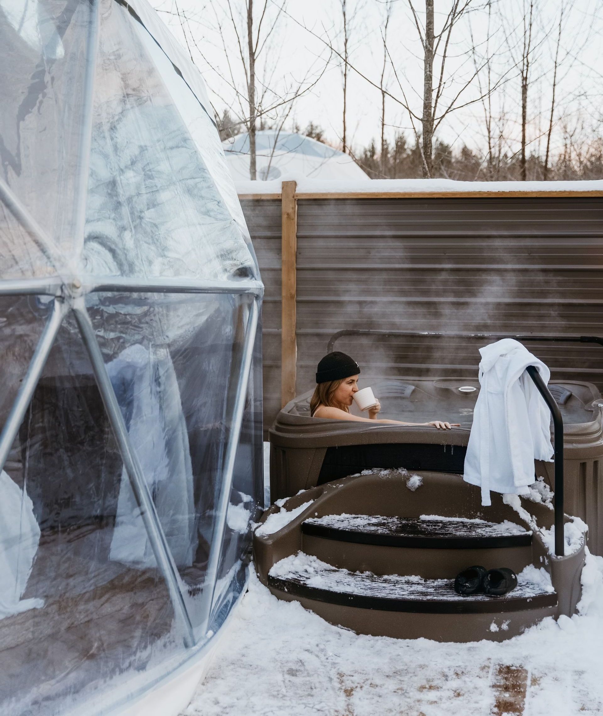 A woman is taking a bath in a hot tub in the snow.