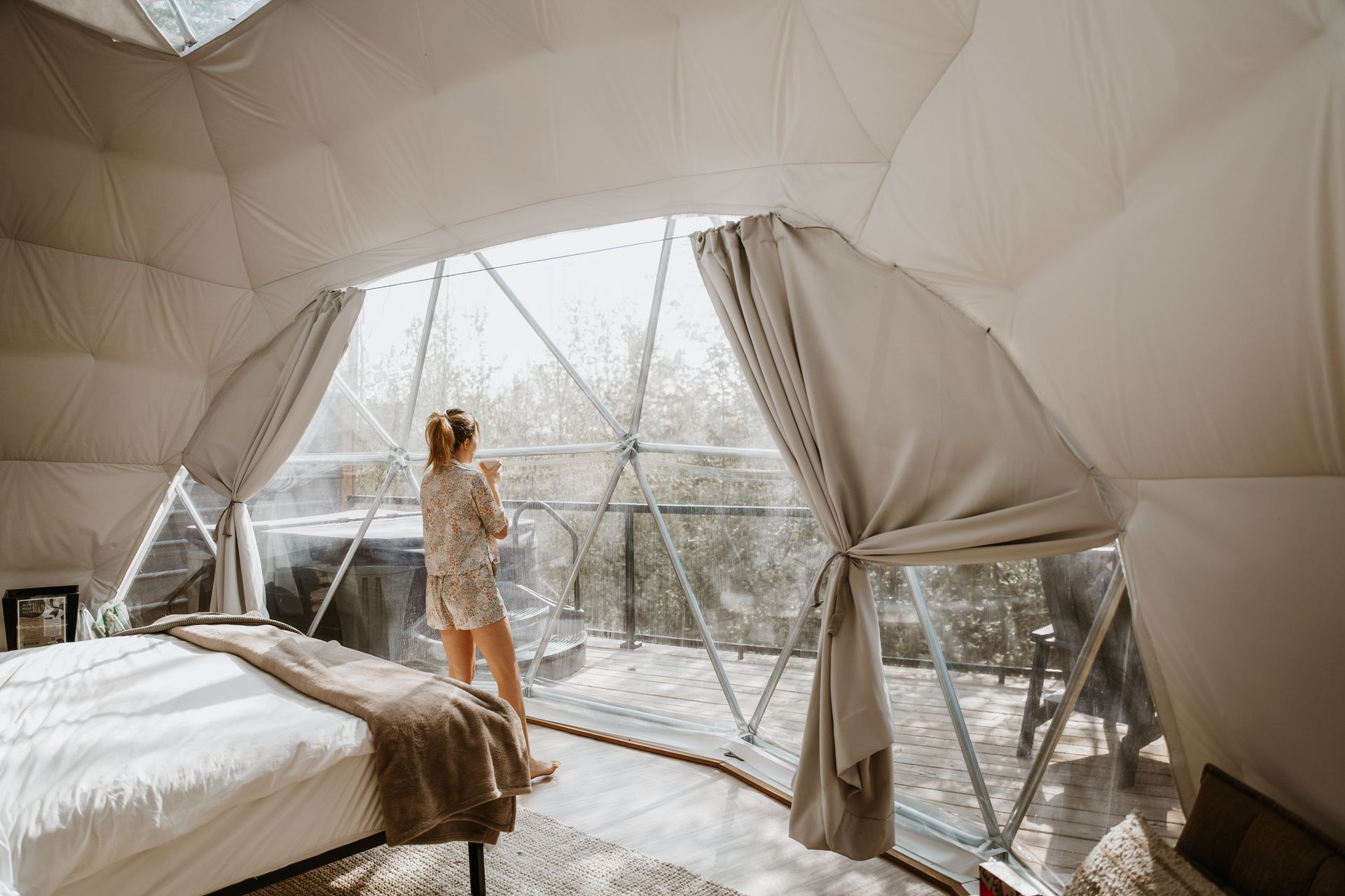 A woman is standing in a dome looking out the window.