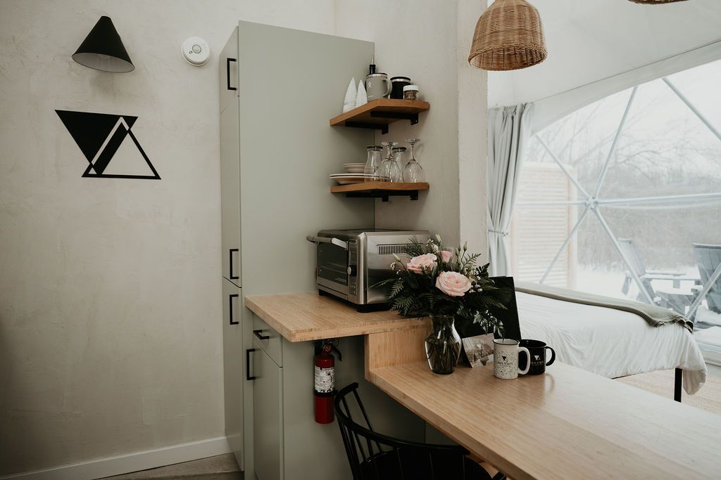 A kitchen with a toaster oven , microwave , and a wooden table.