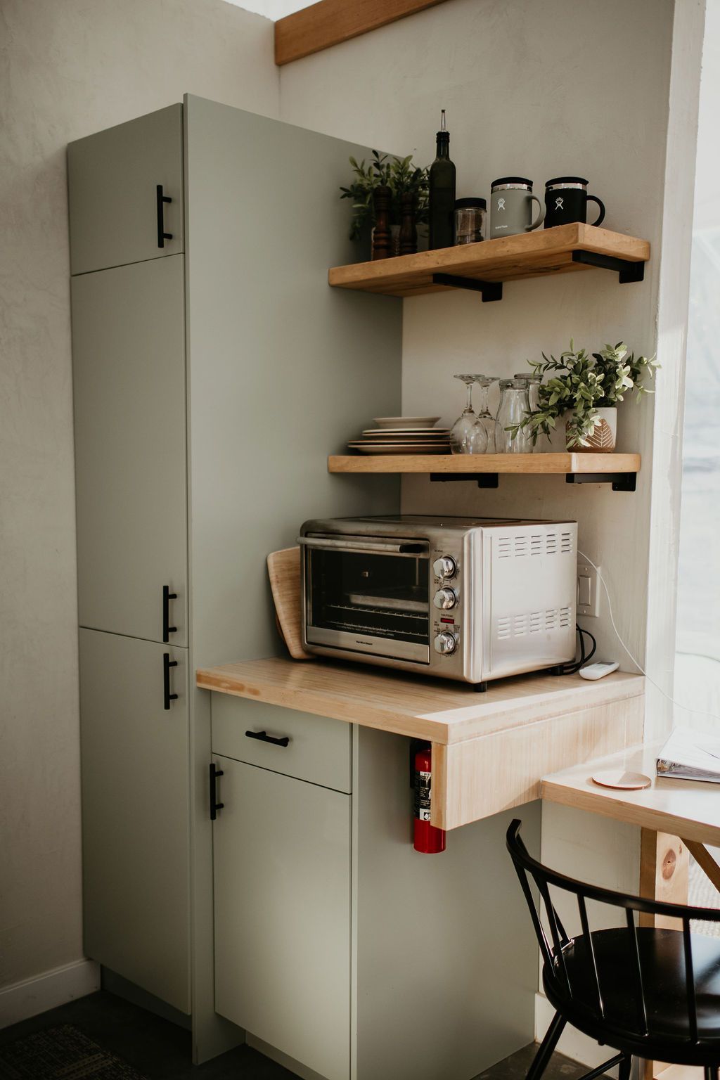 A microwave oven is sitting on a counter in a kitchen next to a window.