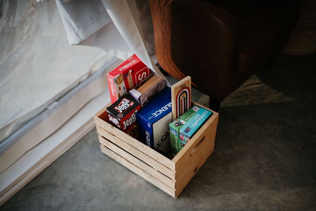 A wooden box filled with candy bars is sitting on the floor next to a window.