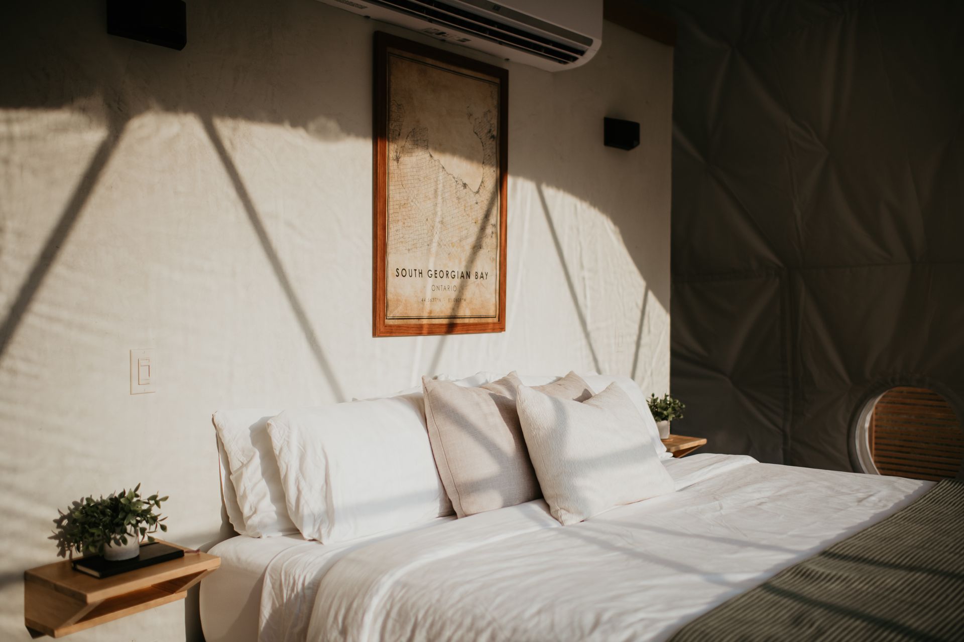 Large  bed with luxury bedding inside sunny room in a glamping dome.