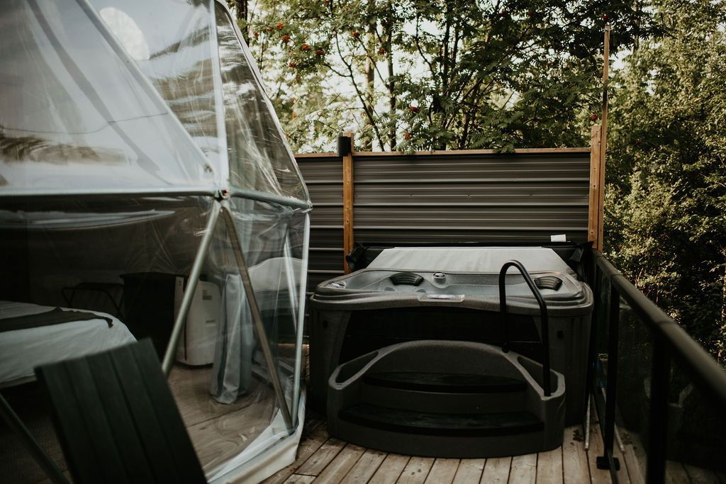 A hot tub is sitting on a deck next to a tent.