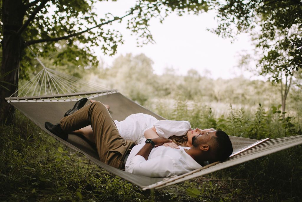 A man is laying in a hammock under a tree.