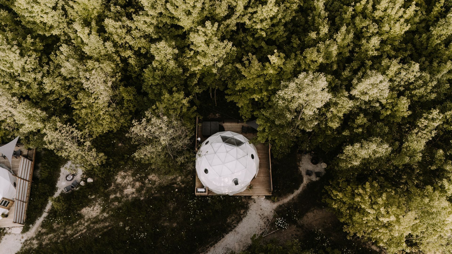 An aerial view of a tent in the middle of a forest.