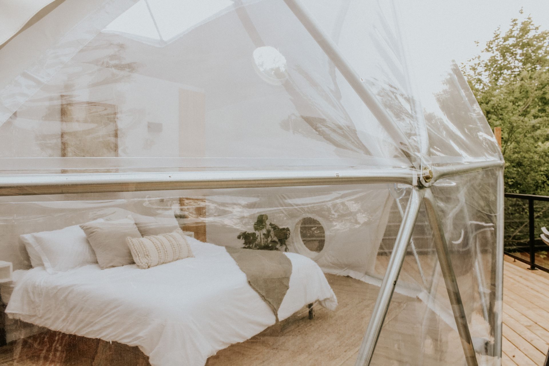 A bed is sitting inside of a clear dome tent.