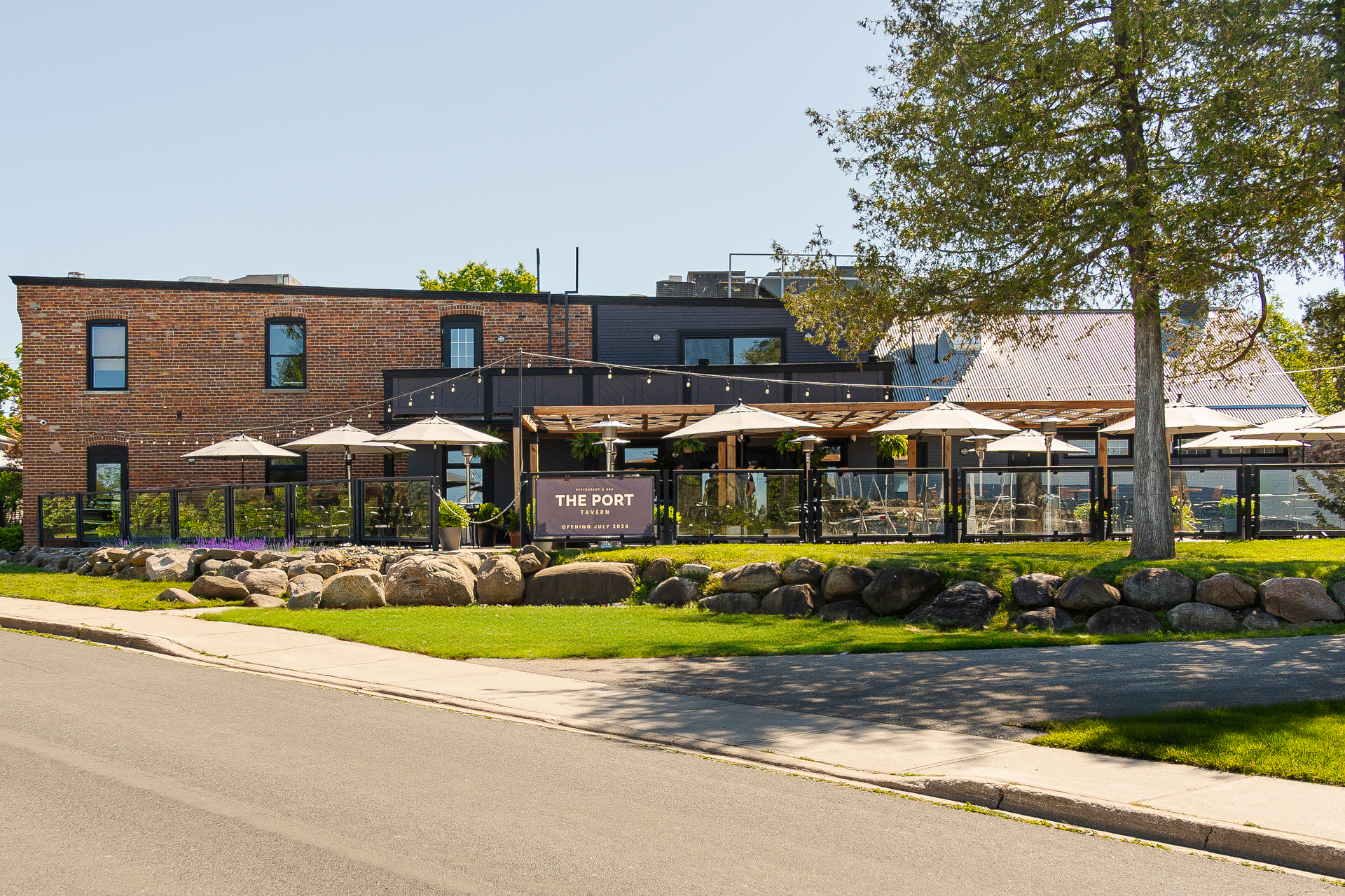 A large brick building with umbrellas and a tree in front of it