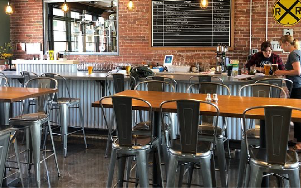 a restaurant with tables and chairs and a railroad crossing sign on the wall .