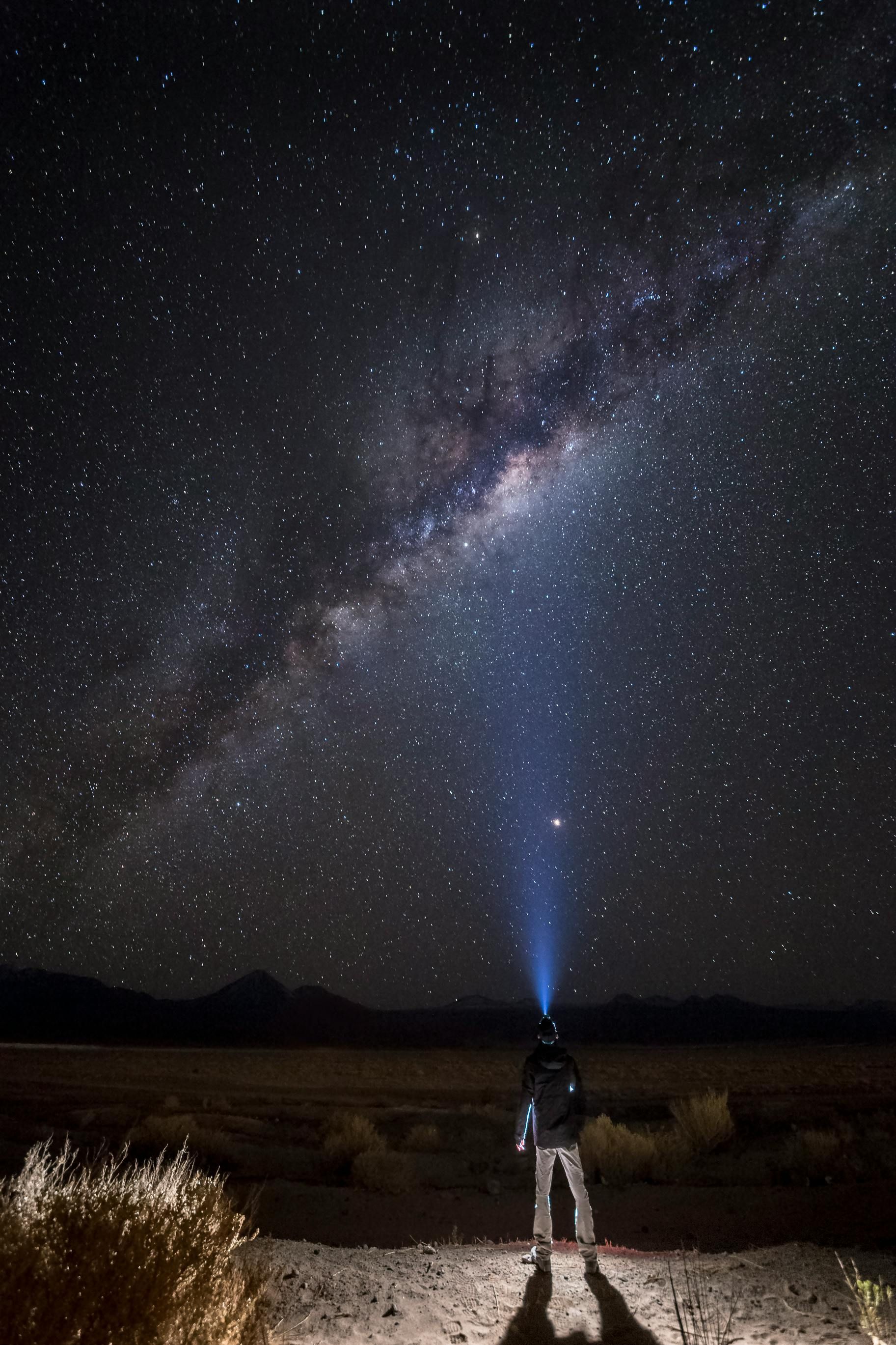 A person with a flashlight looking up at the stars