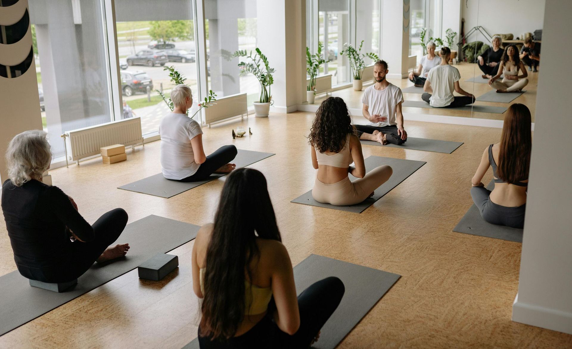 A group of people are sitting on yoga mats in a gym.