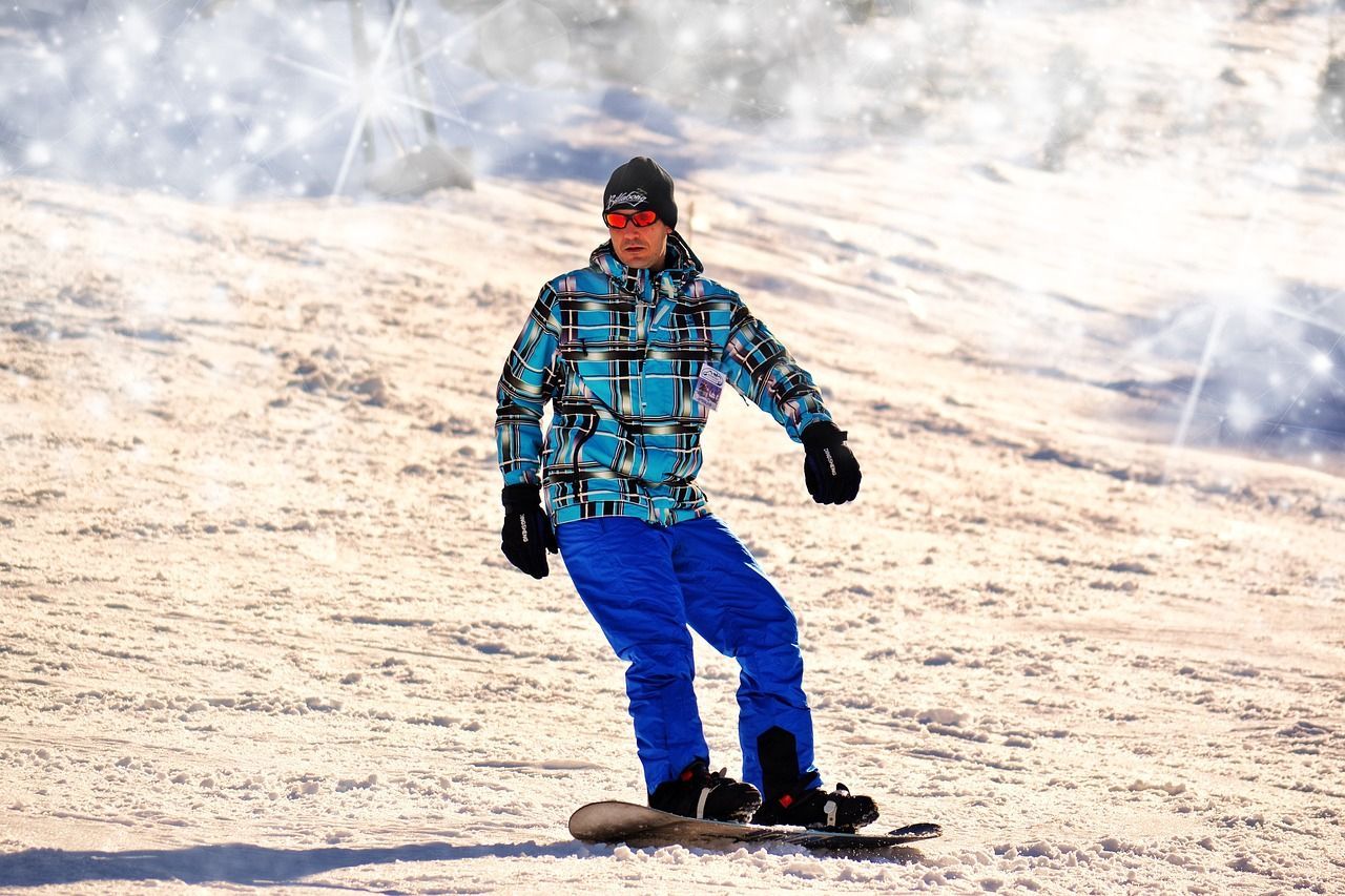 A man is riding a snowboard down a snow covered slope.